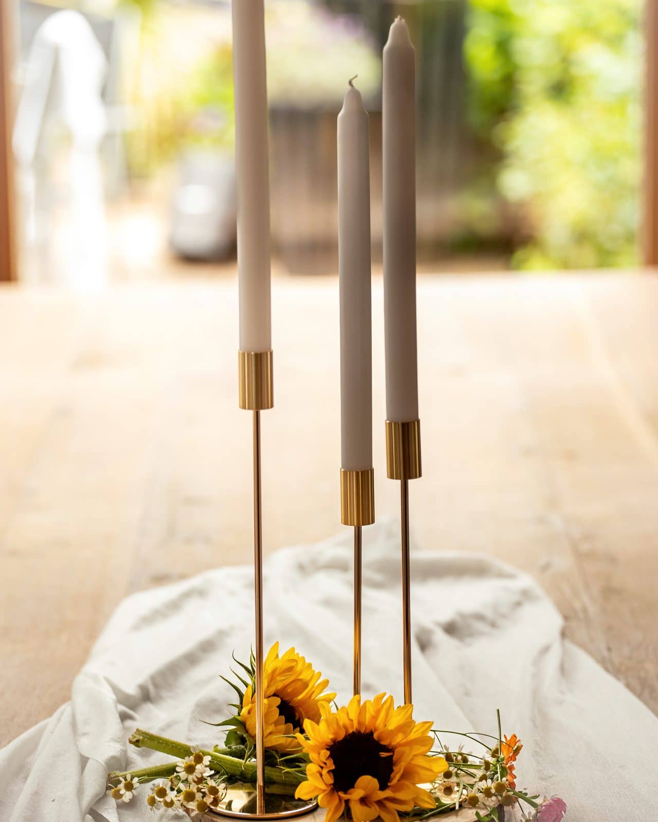 Goldene Kerzenhalter mit Sonnenblume auf Leinen